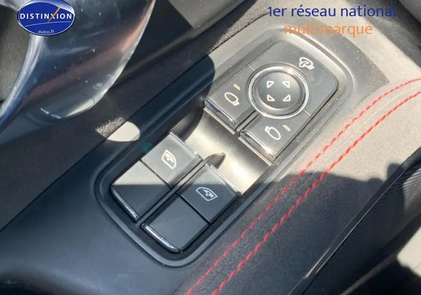 Gros plan sur les commandes de lève-vitres et rétroviseurs côté conducteur avec surpiqûres rouges dans une Porsche Boxster rouge.