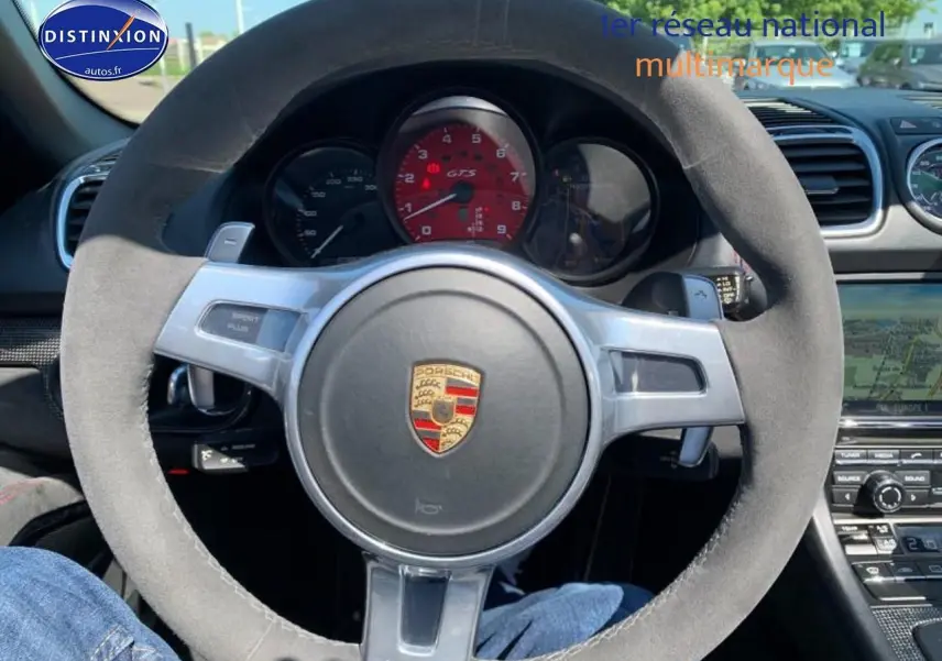 Vue rapprochée du volant en alcantara de la Porsche Boxster 981 GTS avec compte-tours rouge au centre.