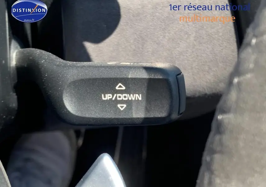 Gros plan sur la commande de palettes au volant marquée "UP/DOWN" dans l'habitacle d'une Porsche Boxster rouge.