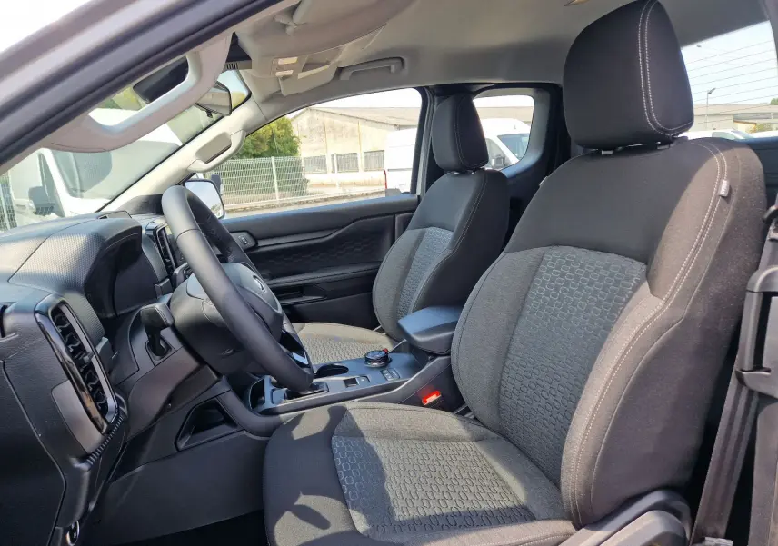 Vue intérieure côté conducteur du Ford Ranger Super Cabine 2026, sièges tissu gris avec console centrale et volant visibles.