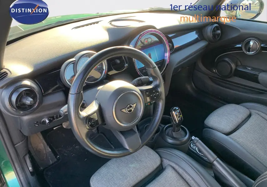 Intérieur de la MINI Cabriolet F57 2023 en British Racing Green, vue côté conducteur avec tableau de bord et volant visibles.