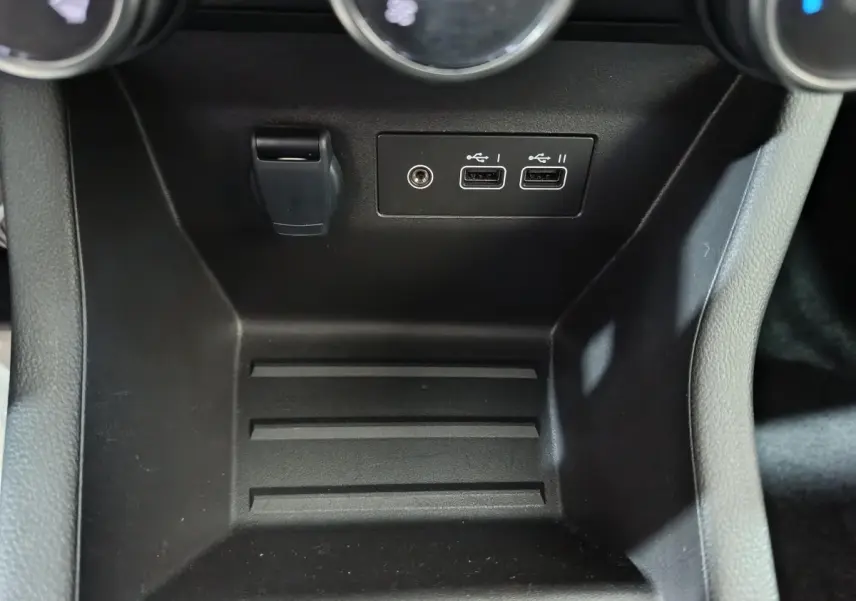 Gros plan sur la console centrale noire de la Renault Clio gris clair, montrant les ports USB et prise 12V.