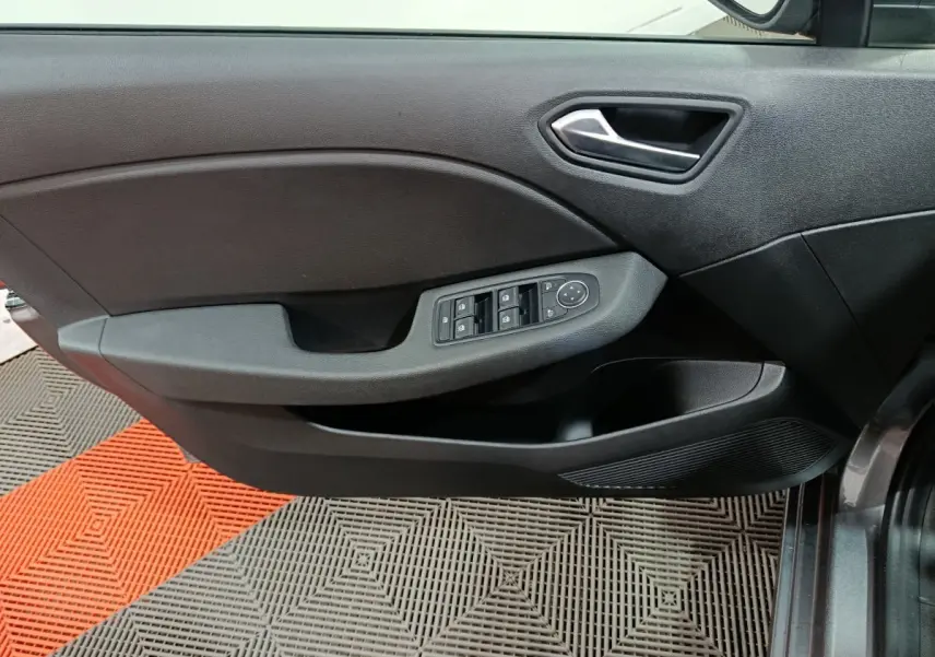 Vue rapprochée de la porte avant droite de la Renault Clio gris clair, avec commandes des vitres et poignée intégrée.