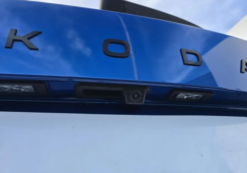 Gros plan sur la caméra de recul intégrée au hayon bleu racing avec lettres noires SKODA, toit noir visible en haut.