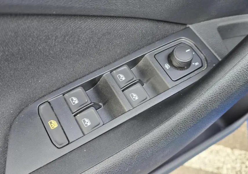 Gros plan sur les commandes des vitres électriques et réglage des rétroviseurs côté conducteur d’une Skoda Kamiq 2025 bleu Racing toit noir.
