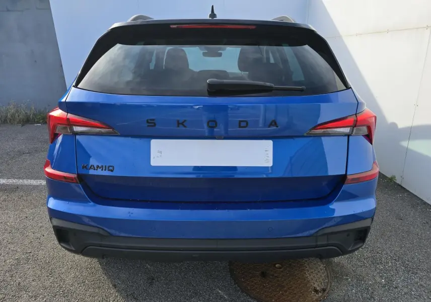 Vue arrière d'un Skoda Kamiq bleu racing avec toit noir et feux arrière LED distinctifs.