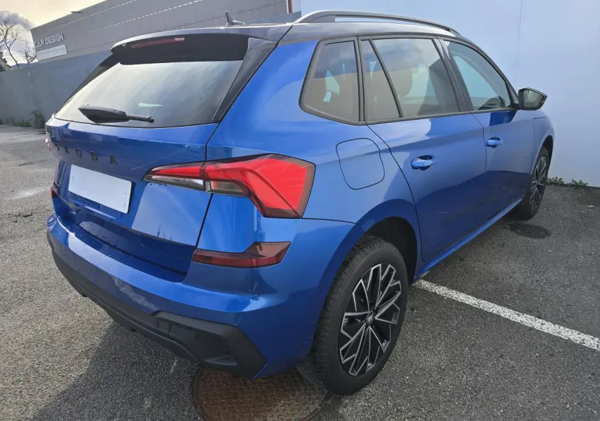 Vue 3/4 arrière droite d'un Skoda Kamiq bleu racing avec toit noir et jantes alliage 17 pouces.