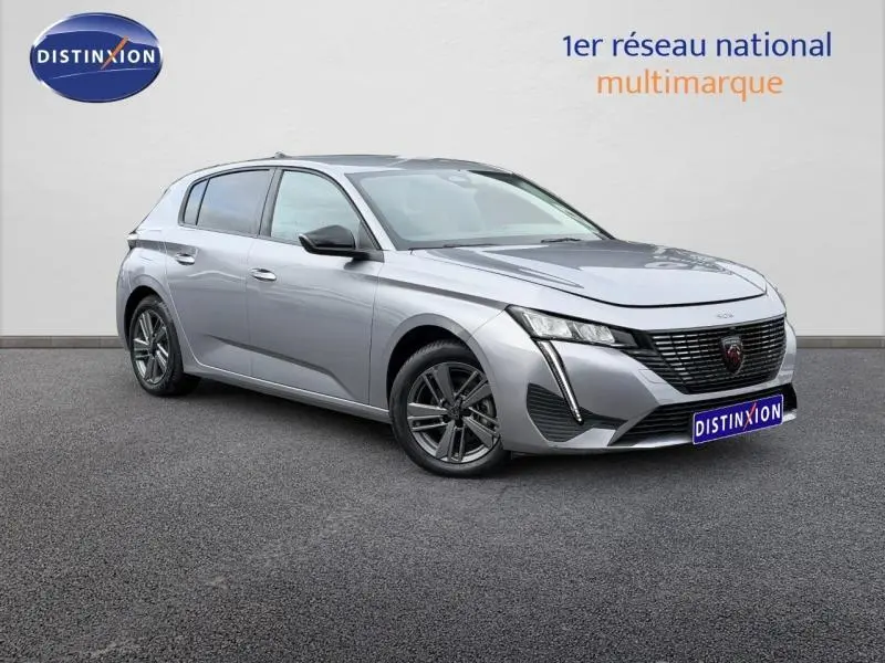 Peugeot 308 gris en 3/4 avant droit, mettant en valeur sa calandre distinctive et ses phares LED fins.