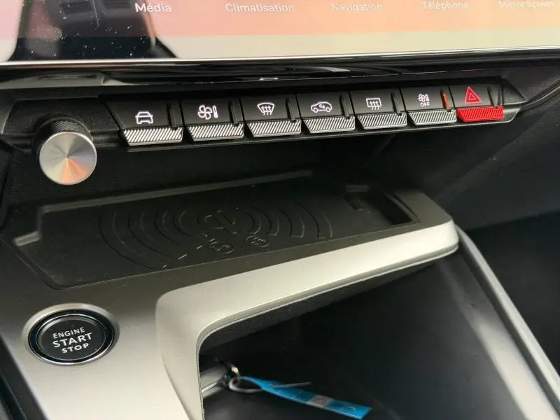 Gros plan sur la console centrale de la Peugeot 308 2024 gris, montrant les boutons de commande et le bouton start/stop.
