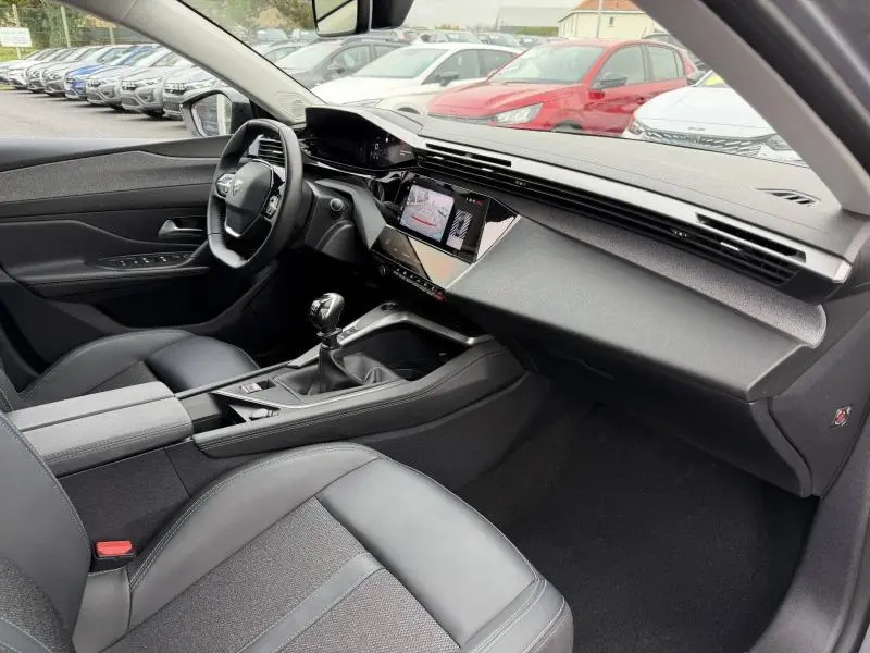 Intérieur de la Peugeot 308 2024 en vue 3/4 avant droit, avec tableau de bord moderne et boîte manuelle visible.