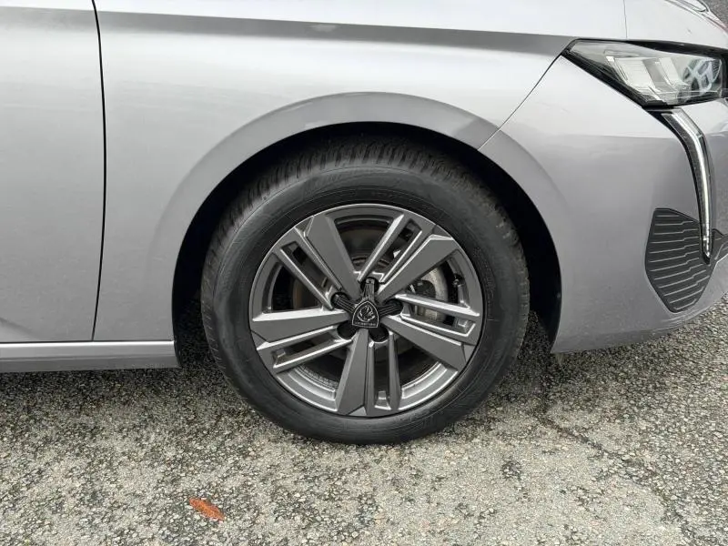 Gros plan sur la roue avant droite et une partie du pare-chocs gris du Peugeot 308 2024 avec feux LED distinctifs.