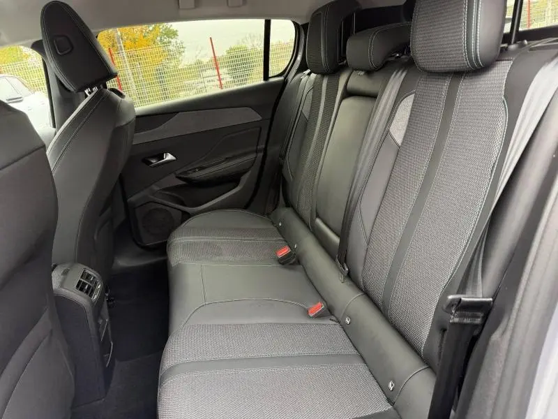 Vue intérieure côté droit des sièges arrière gris de la Peugeot 308 1.2 PureTech 130ch Allure 2024 avec finitions tissu et cuir.