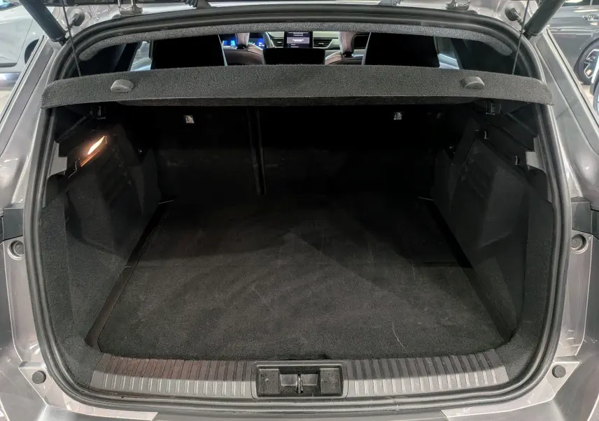Coffre ouvert vu de l'arrière d'une Renault Symbioz gris Cassiopé, intérieur noir et tablette cache-bagages visible.
