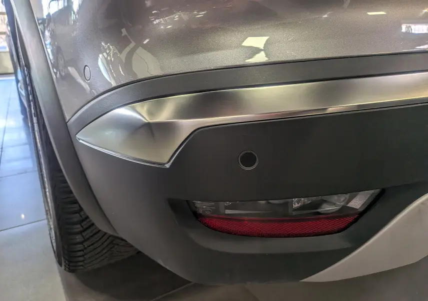 Gros plan sur l’angle arrière droit du Renault Symbioz gris Cassiopé, mettant en valeur le feu arrière et le pare-chocs avec capteur de recul.