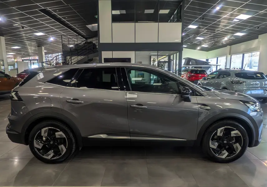 Vue de profil côté gauche d’un Renault SYMBIOZ gris Cassiopé avec jantes bicolores en concession.