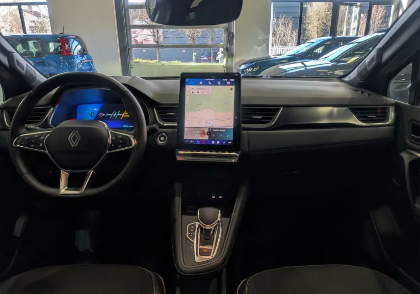 Vue intérieure avant du Renault Symbioz E-TECH avec tableau de bord noir, écran tactile vertical et volant multifonction.