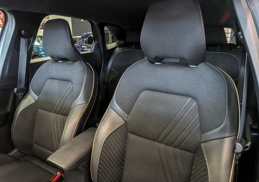 Vue intérieure rapprochée des sièges avant en tissu et cuir noir avec surpiqûres claires du Renault Symbioz E-TECH 2025.