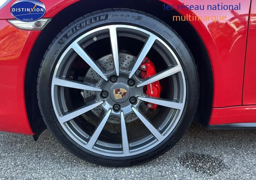 Gros plan sur la roue avant droite rouge d'une Porsche 911 (991) Carrera 4 PDK avec étrier de frein rouge et jante alu.