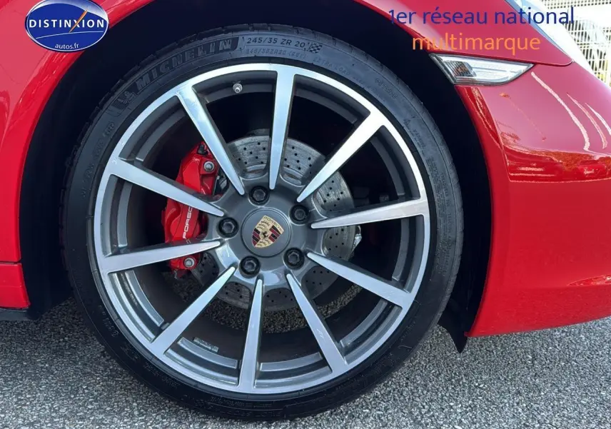 Gros plan sur la roue avant gauche de la Porsche 911 rouge (991) avec étrier de frein rouge et jante alu multibranches.