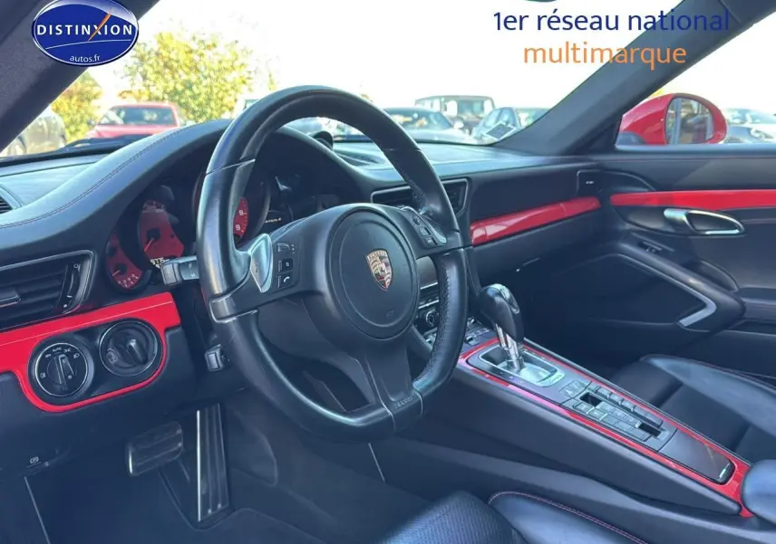 Vue intérieure côté conducteur de la Porsche 911 (991) Carrera 4 PDK 2013, avec tableau de bord et inserts rouges.