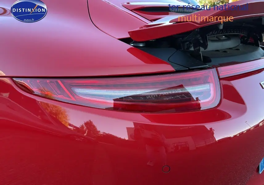 Gros plan sur le feu arrière droit et le becquet relevé d'une Porsche 911 Carrera 4 rouge de 2013.