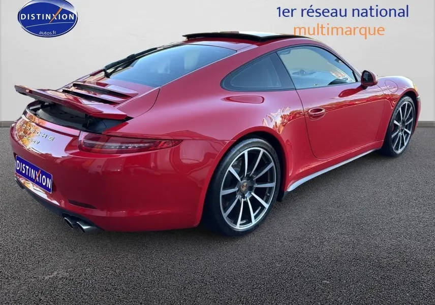 Vue 3/4 arrière droite d'une Porsche 911 (991) Carrera 4 PDK rouge avec becquet arrière relevé et jantes alu.