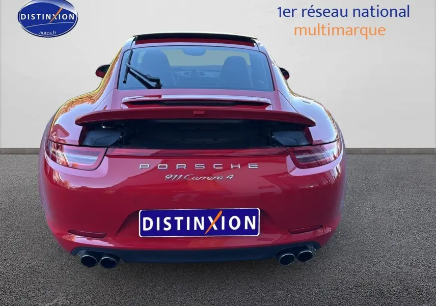 Vue arrière d'une Porsche 911 Carrera 4 rouge de 2013 avec becquet relevé et double sortie d'échappement chromée.