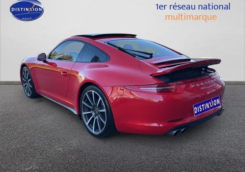 Vue 3/4 arrière droite d'une Porsche 911 Carrera 4 rouge avec becquet arrière déployé et jantes alu.