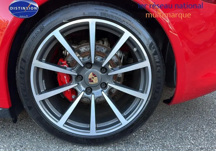 Gros plan sur la jante alu grise et le frein rouge d’une Porsche 911 (991) Carrera 4 PDK rouge.