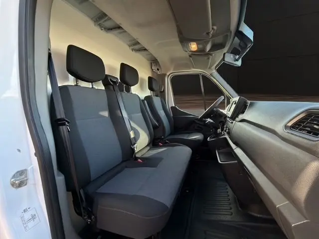 Vue intérieure côté conducteur du Renault Master blanc 2023, montrant les sièges avant gris et le tableau de bord.