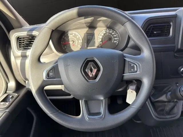 Vue rapprochée du volant noir de Renault Master 2023 avec commandes intégrées et tableau de bord en arrière-plan.