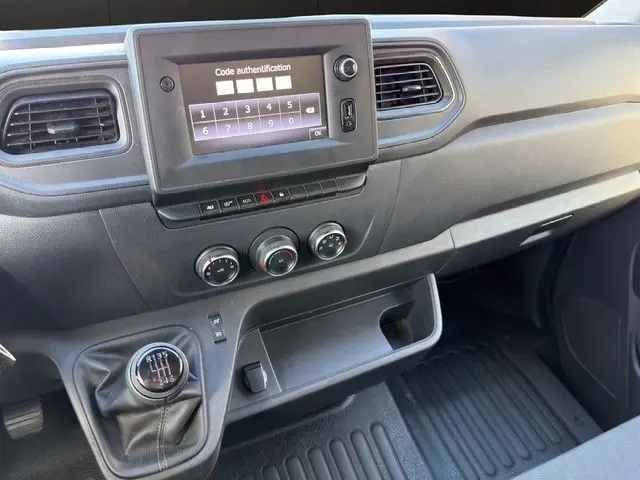 Vue intérieure du tableau de bord du Renault Master blanc 2023, avec écran tactile, commandes de climatisation et levier de vitesses manuel.
