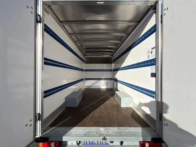 Vue intérieure arrière du coffre blanc du Renault Master 2023, montrant un espace de chargement vide avec rails bleus sur les parois.