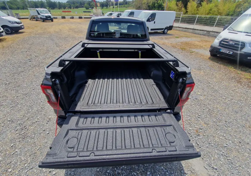 Vue arrière d'un Ford Ranger Super Cabine gris carbone avec plateau ouvert et rideau rigide coulissant visible.