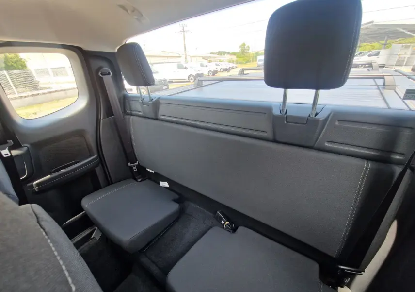 Vue intérieure arrière côté droit du Ford Ranger Super Cabine 2026, sièges arrière rabattus en tissu noir.