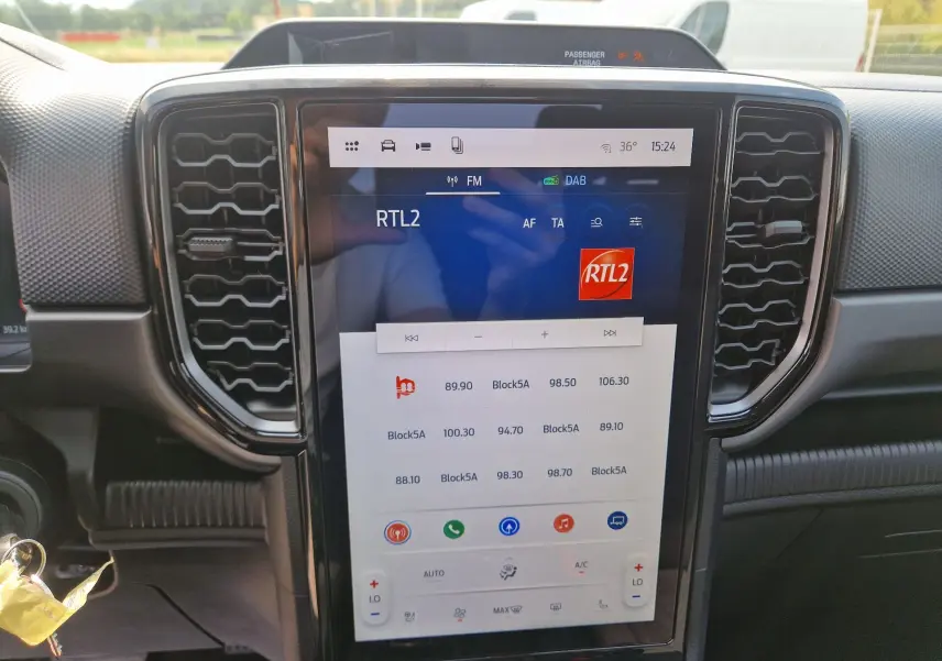 Vue rapprochée de l’écran tactile 12,4'' central du Ford Ranger Super Cabine gris carbone, avec commandes climatisation et radio visibles.