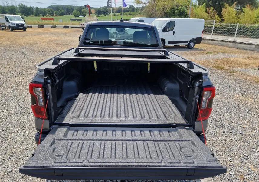 Vue arrière d'un Ford Ranger Super Cabine gris carbone avec plateau ouvert et rideau rigide coulissant visible.