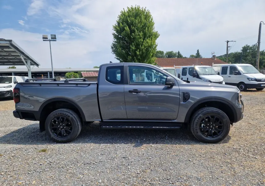 Vue latérale droite d'un Ford Ranger Super Cabine gris carbone avec marchepied et rideau de plateau rigide.
