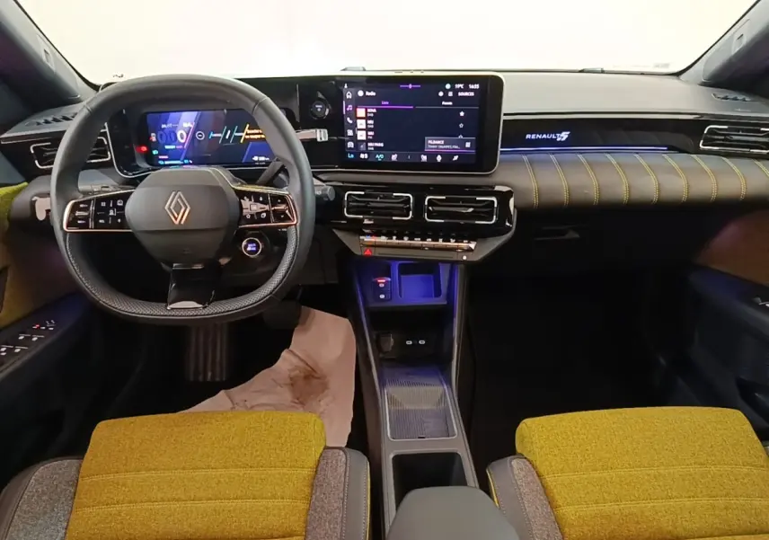 Vue intérieure avant de la Renault R5 Iconic 2024 avec tableau de bord numérique et sièges jaunes texturés.