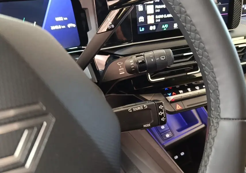 Vue rapprochée du volant et du tableau de bord numérique de la Renault R5 électrique 2024 avec éclairage bleu intérieur.