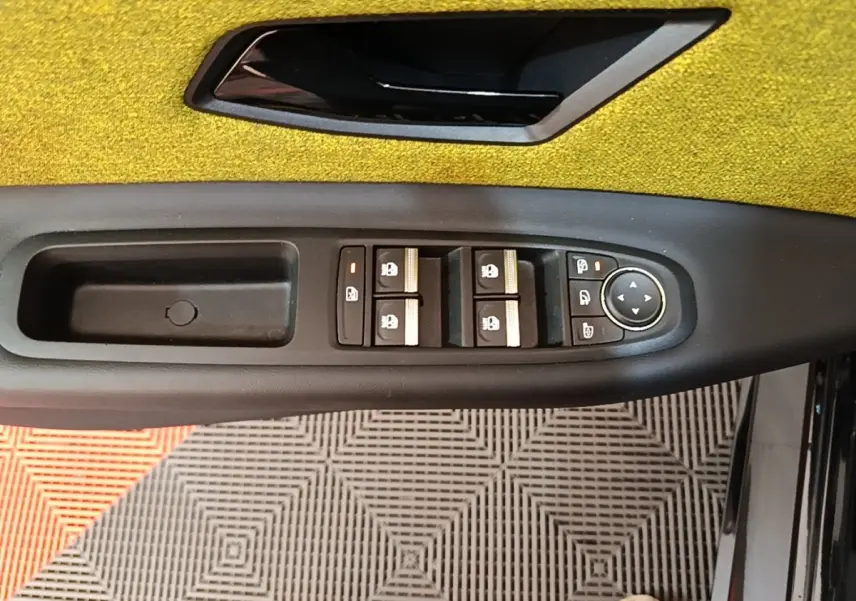 Détail de la commande des vitres et rétroviseurs côté gauche intérieur de la Renault R5 2024 avec garniture jaune.