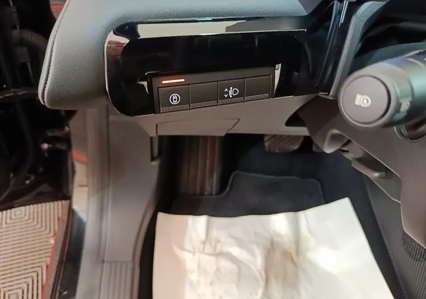 Vue rapprochée côté gauche du tableau de bord noir avec boutons de réglage des phares et verrouillage sur Renault R5 électrique 2024.