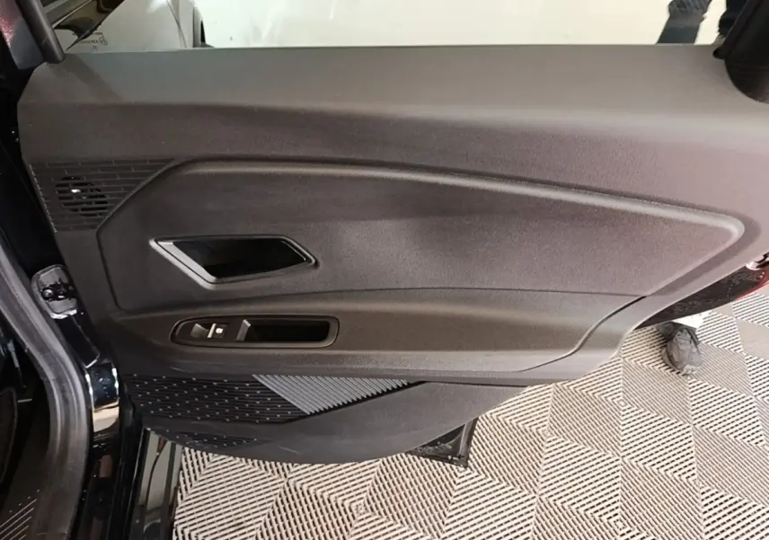 Intérieur côté gauche de la porte avant d'une Renault R5 électrique 2024, avec panneau noir et commandes fenêtres.