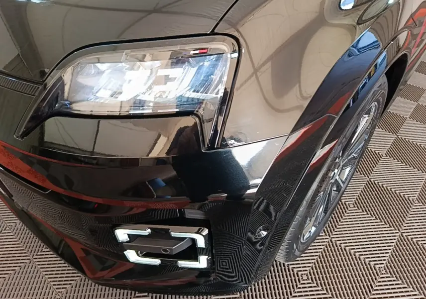 Gros plan sur l'avant droit noir brillant de la Renault R5 électrique 2024, mettant en valeur le phare LED et la roue.