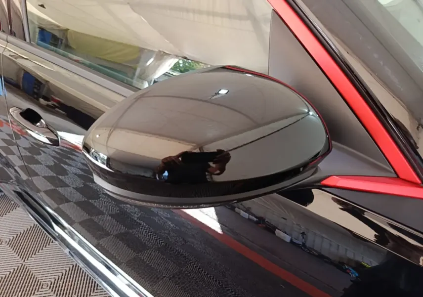 Rétroviseur noir brillant côté gauche de la Renault R5 Iconic 2024 avec cadre rouge distinctif autour de la vitre.