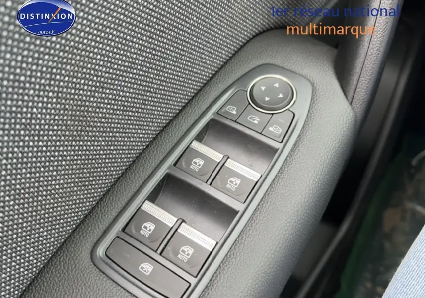 Gros plan sur les commandes des vitres électriques et rétroviseurs d'une Renault Symbioz gris schiste, côté conducteur.