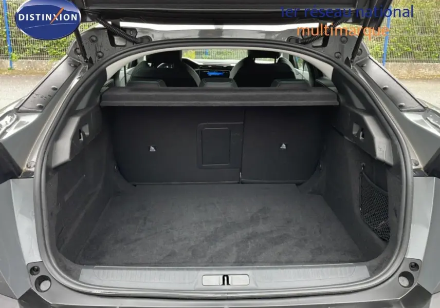 Coffre ouvert vu de l'arrière d'une Peugeot 408 gris selenium metal, montrant un espace de chargement spacieux et propre.