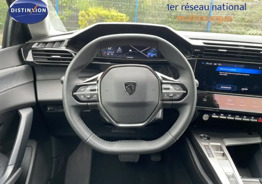 Vue intérieure centrée sur le volant multifonction de la Peugeot 408 1.2 Hybrid 2025 avec tableau de bord numérique.