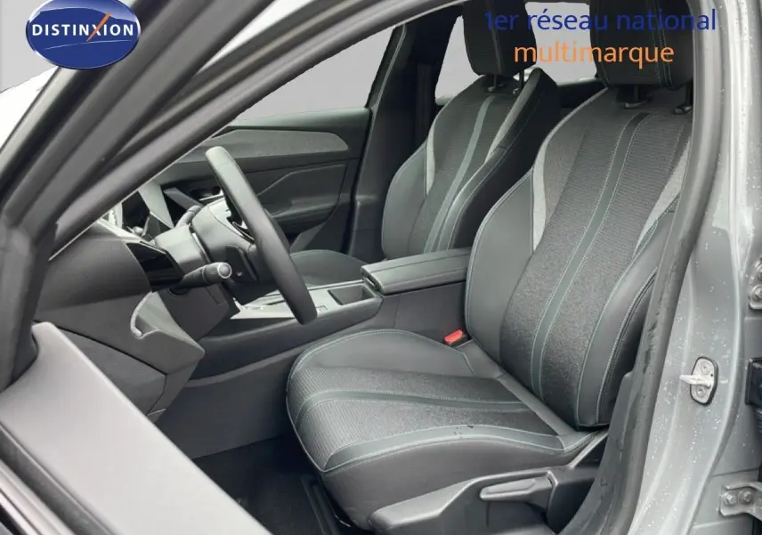 Vue intérieure côté conducteur de la Peugeot 408 gris selenium, montrant sièges tissu et cuir avec surpiqûres bleues.