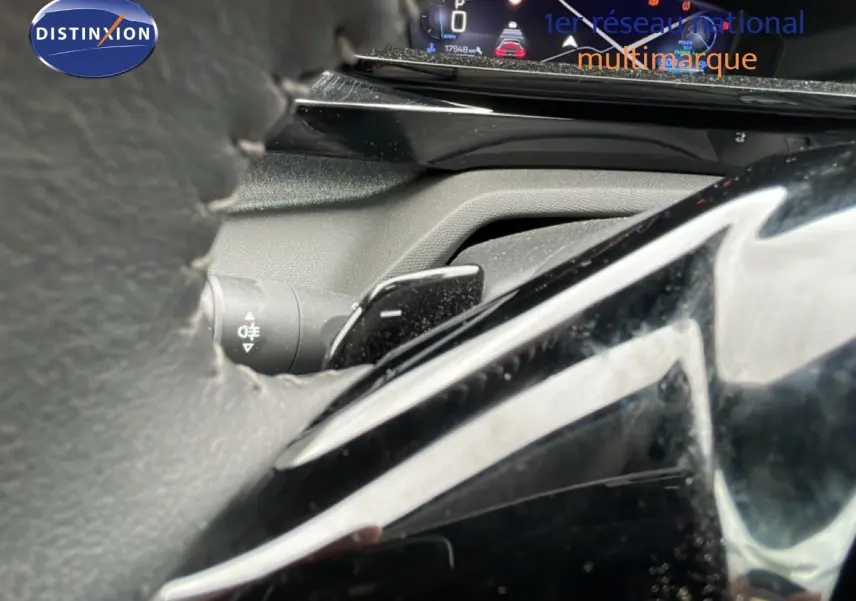 Gros plan sur le volant et le combiné d'instruments numérique de la Peugeot 408 1.2 Hybrid 2025, intérieur gris noir.